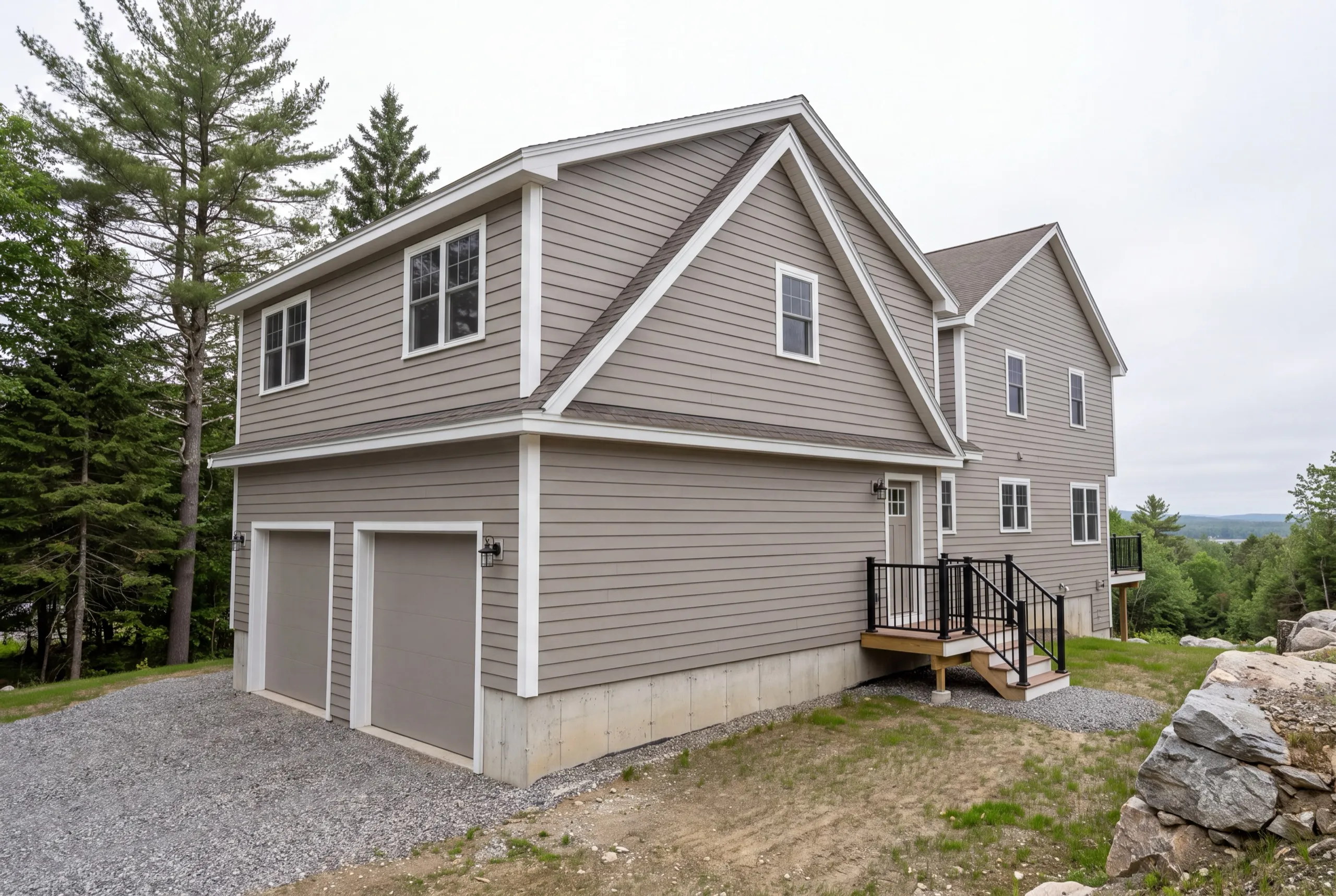 ADU builder Farmingdale Maine: gray two-story wing with a two-bay garage below living space, joined to a house