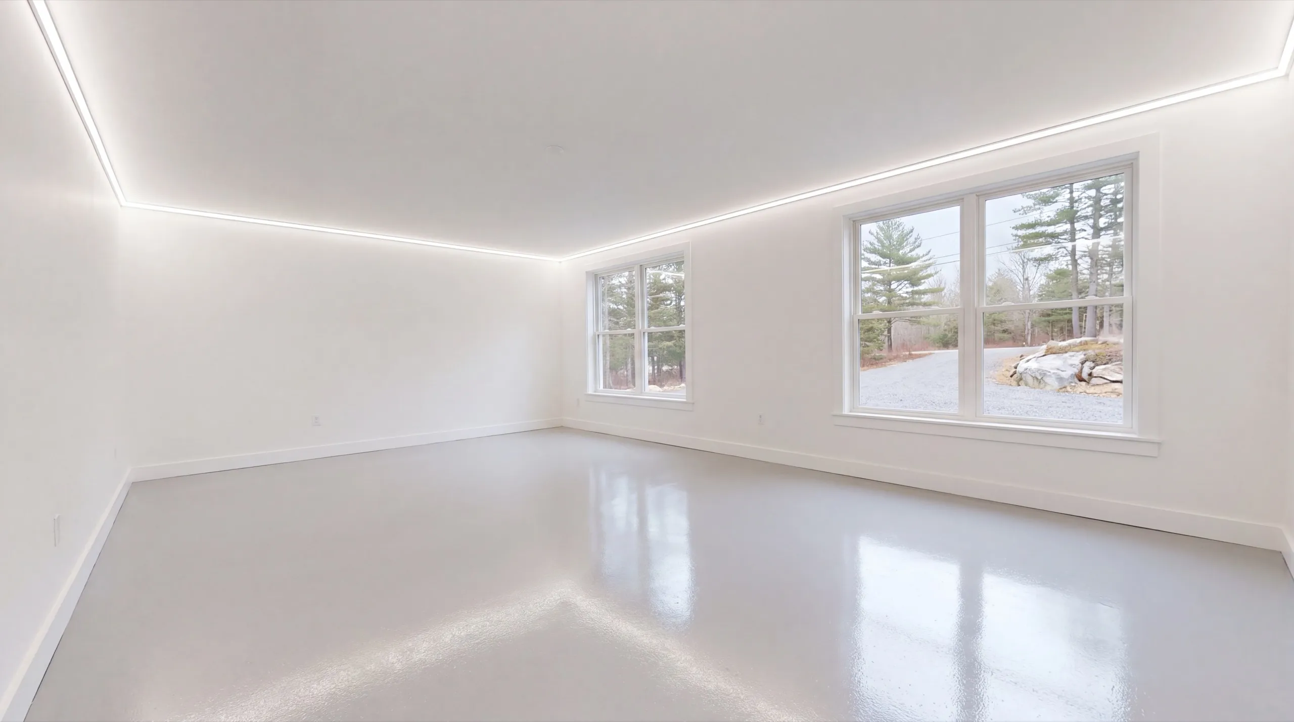 Garage remodeling in Wiscasset, ME: finished empty room with white walls, cove lighting and a glossy gray floor
