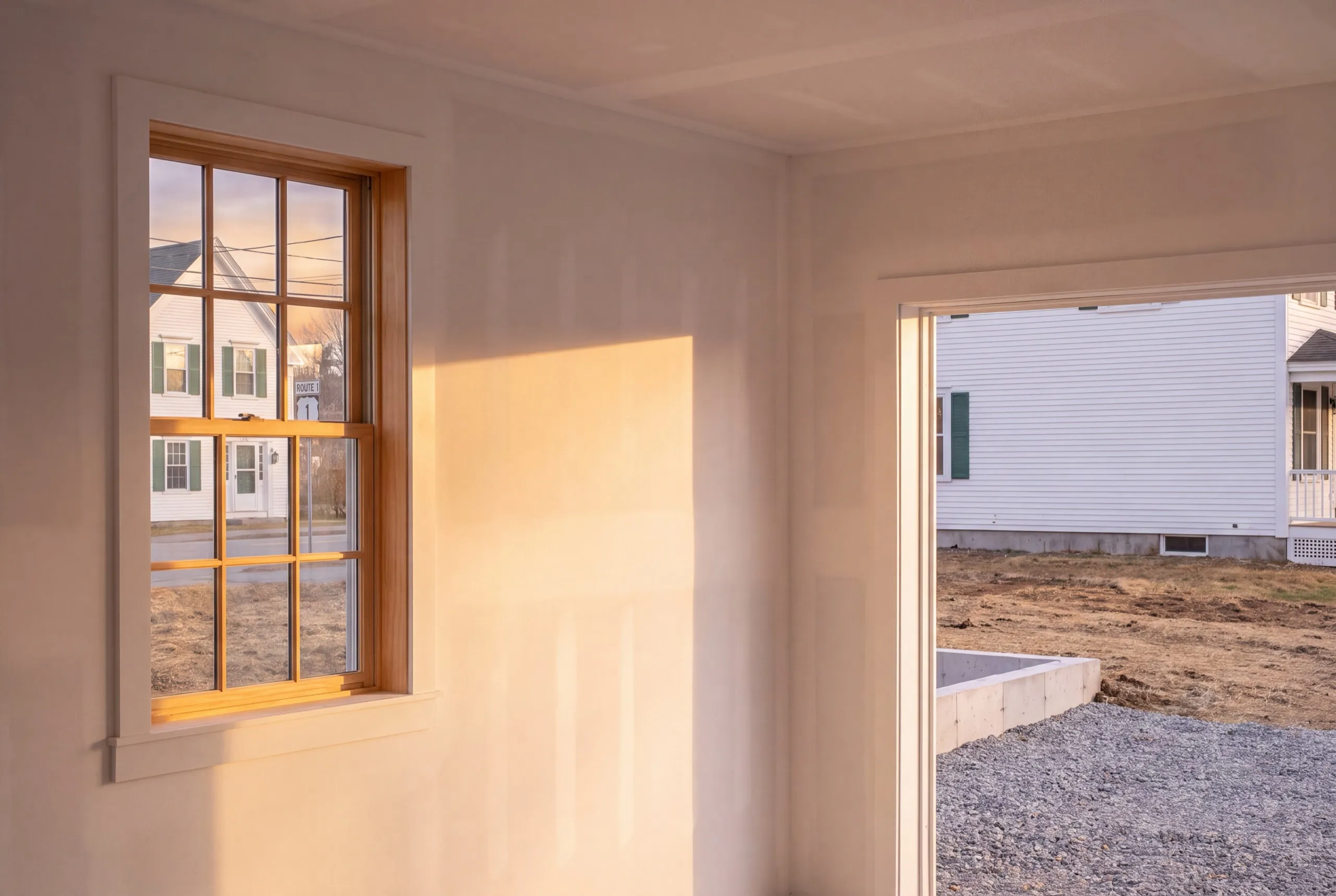 Garage renovation contractor Wiscasset Maine: drywalled garage interior with a wood window and a wide opening to the drive
