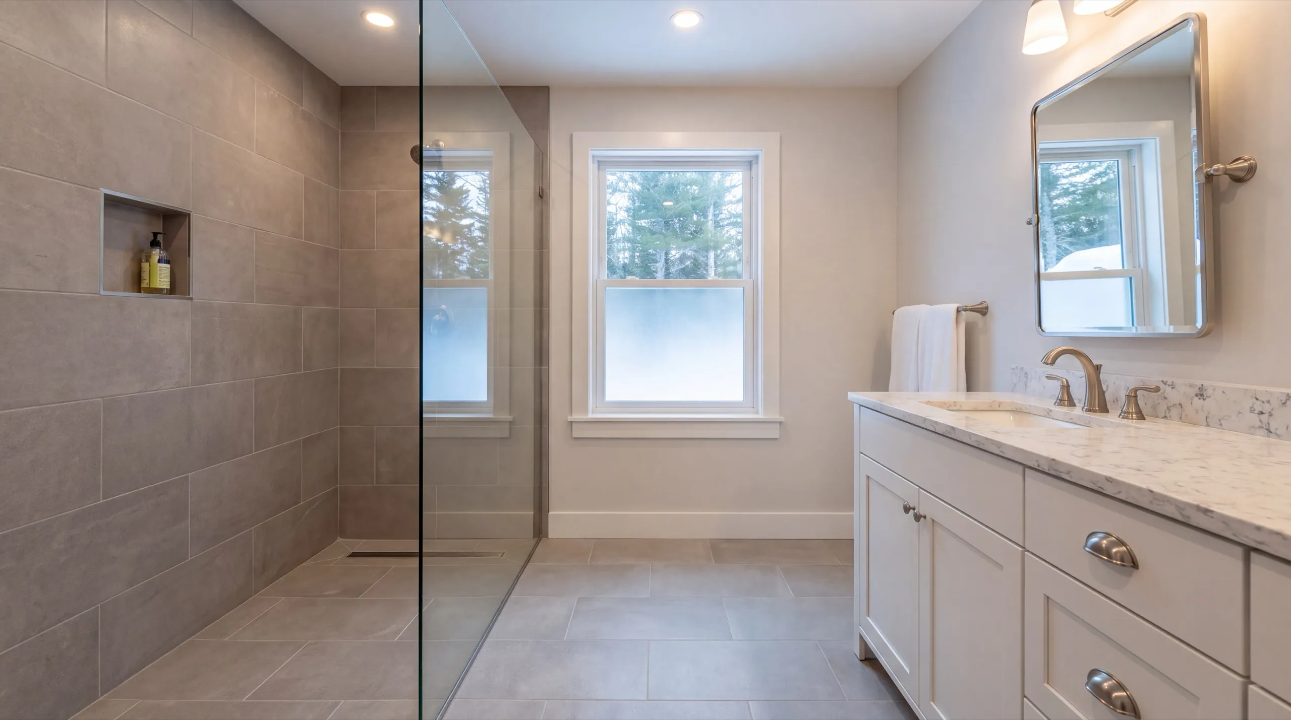 Remodeling Dresden Maine: bathroom with a gray tiled walk-in shower, glass panel and a white vanity