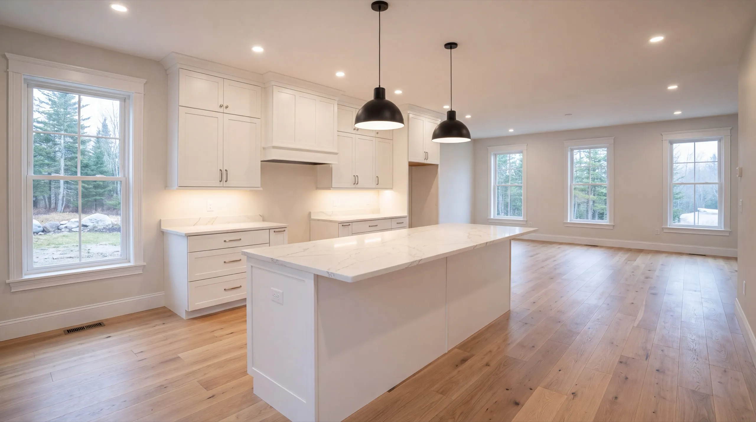 Remodeling in Dresden, ME: finished white kitchen with a large island, black pendants and oak floor