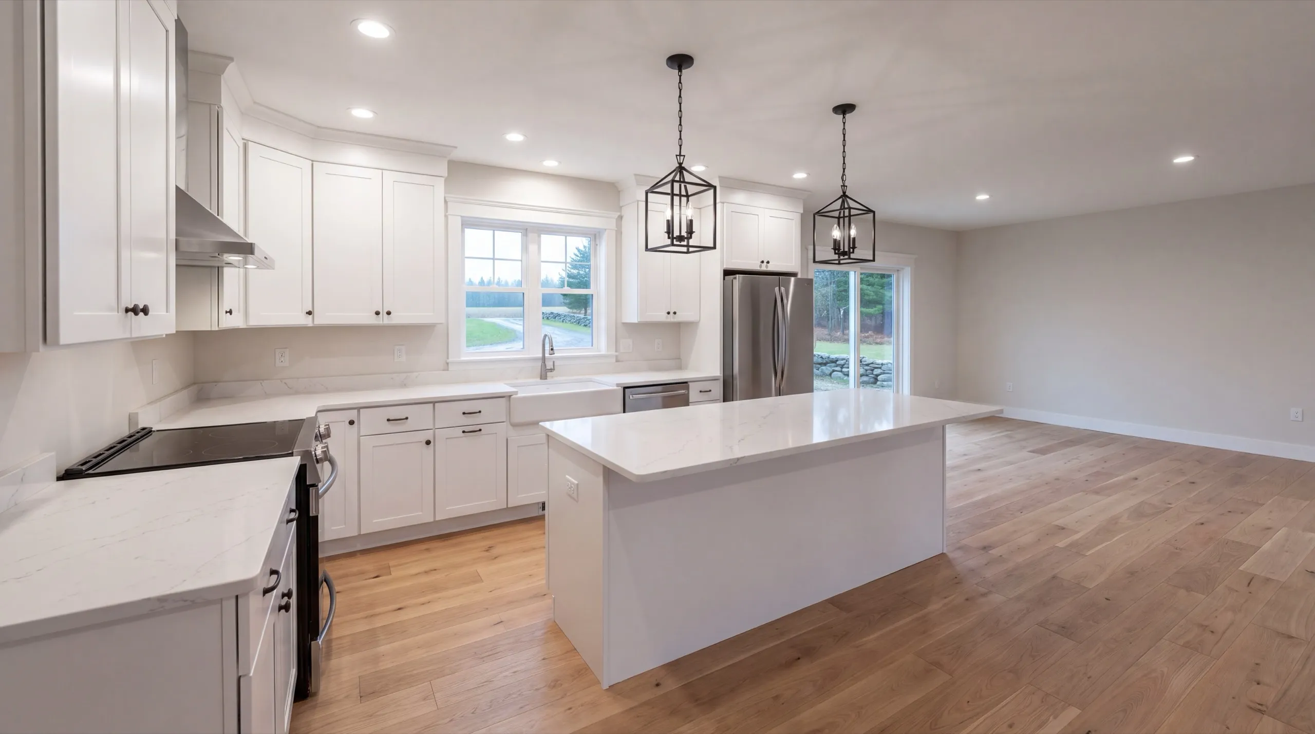 Remodeling in Sidney, ME: finished white kitchen with an island, lantern pendants and a steel fridge