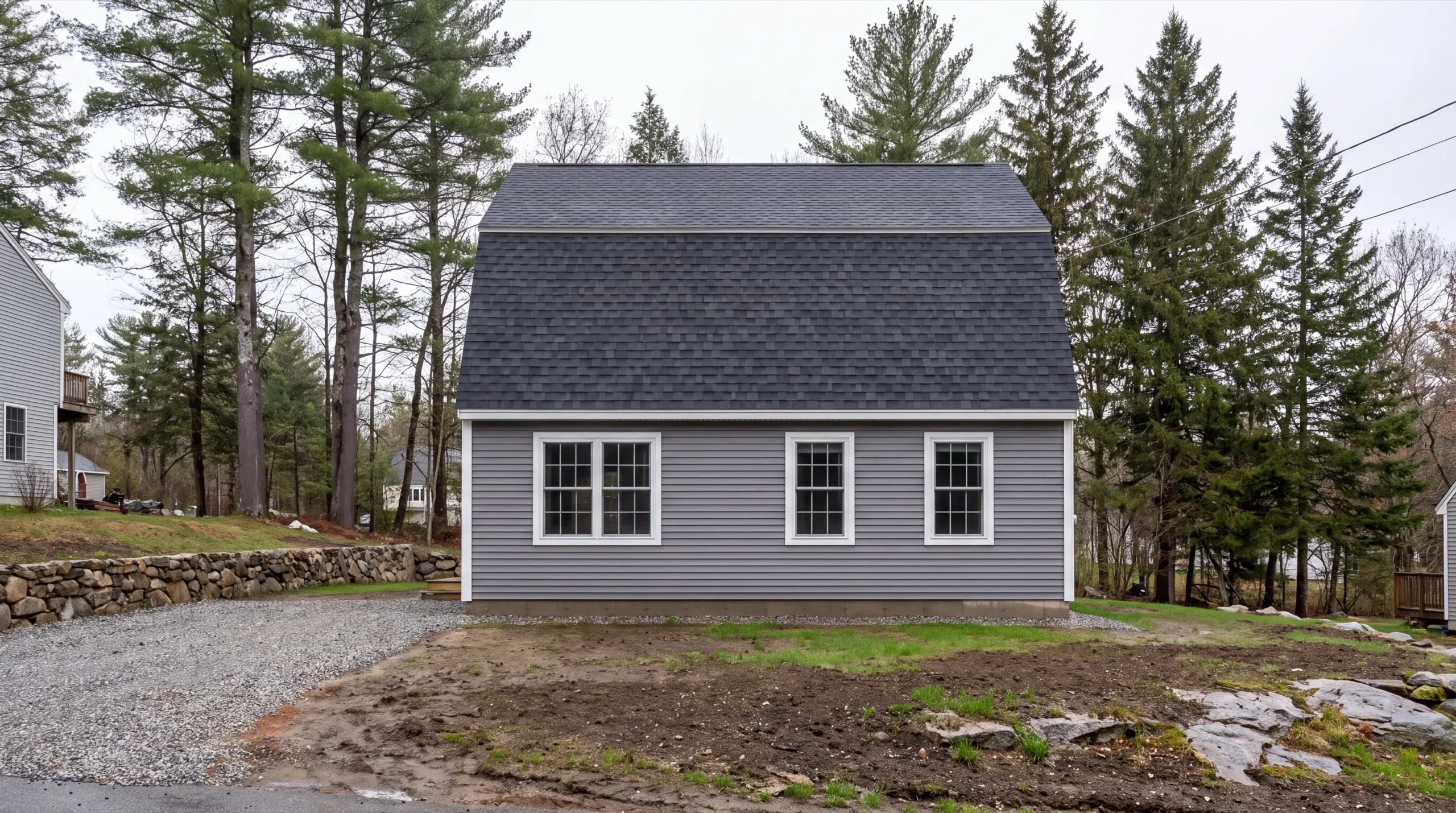 Siding contractor in Gardiner, ME: finished gambrel-roof house with gray siding and white windows on a new lot